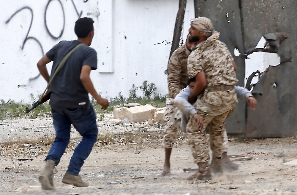Fighters loyal to the Libyan internationally-recognized Government of National Accord (GNA) carry a wounded comrade during clashes against forces loyal to strongman Khalifa Haftar, on Tuesday in the Salah Al-Din area south of the Libyan capital Tripoli. — AFP