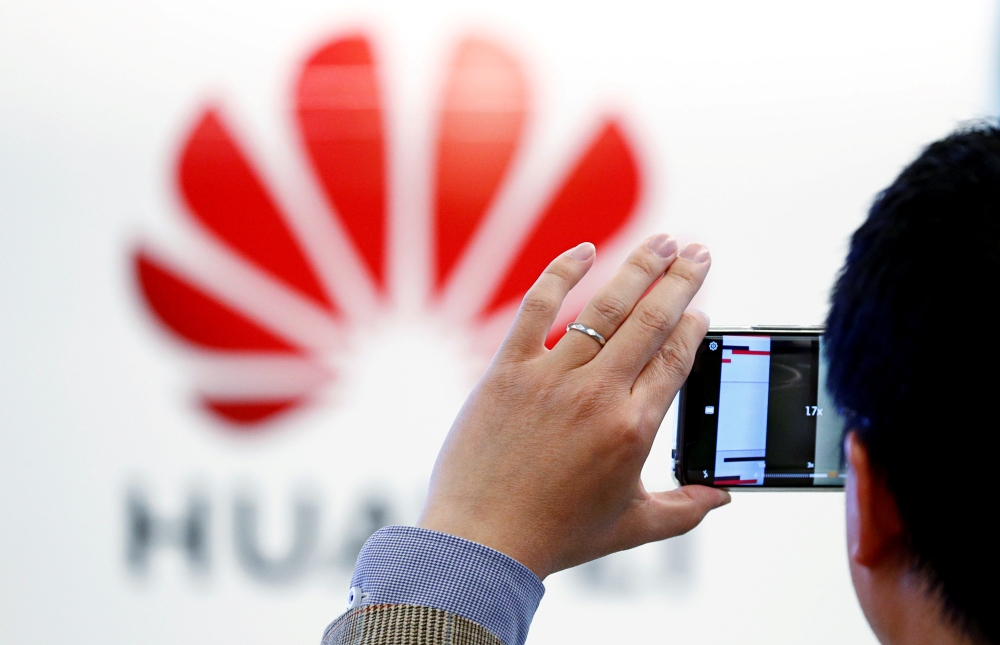 A man takes a picture of a Huawei logo at the Huawei European Cybersecurity Center in Brussels, Belgium. — Reuters