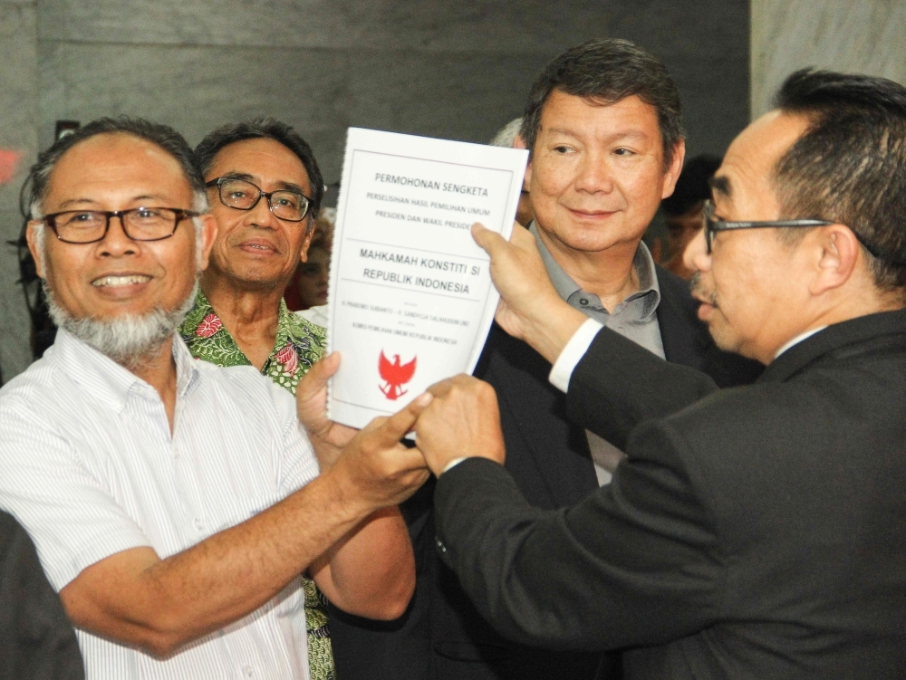 The brother's of former general and president candidate Prabowo Subianto, Hashim Djojohadikusumo, second right, and their lawyer Bambang Widjojanto, left, submit a lawsuit to the constitutional court in Jakarta, on Friday, regarding a presidential election results dispute. — AFP