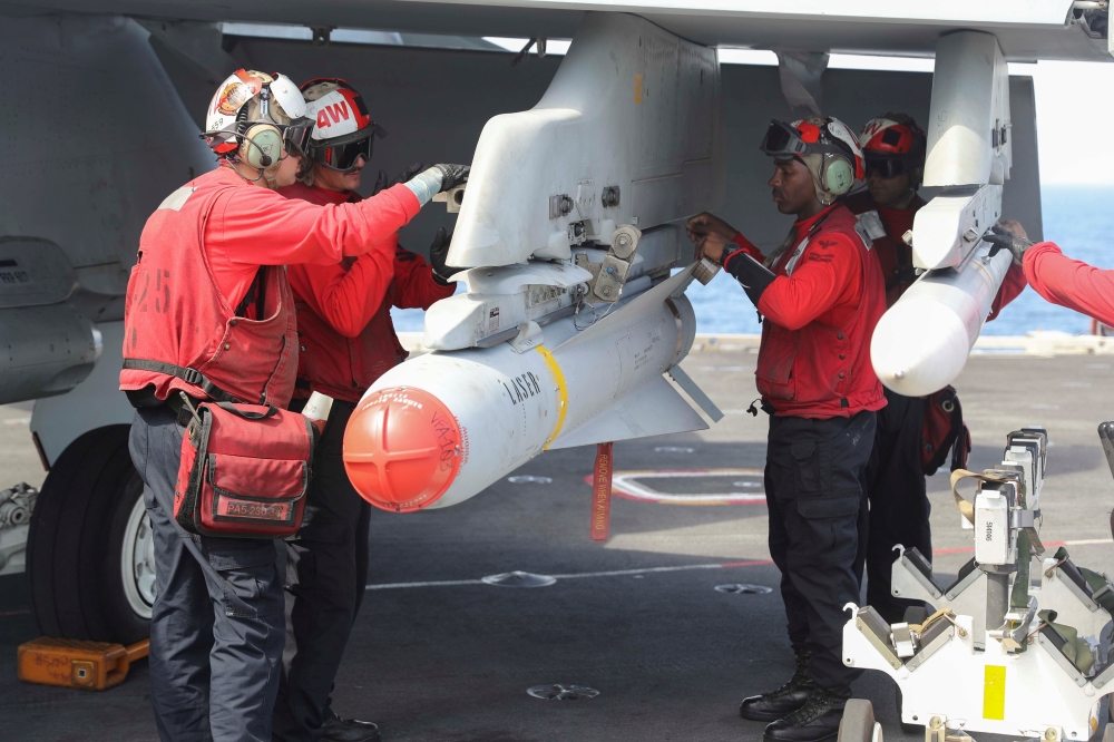 Flight dec crew remove ordnance from an F/A-18E Super Hornet on the flight deck of the aircraft carrier USS Abraham Lincoln (CVN 72), in Arabian Sea. — Reuters