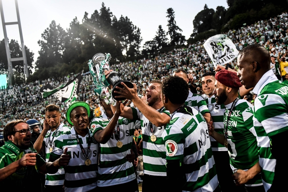 Sporting's Macedonian defender Stefan Ristovski, center, holds the trophy and celebrates with his teammates and supporters after winning Portugal's Cup final football match between Sporting CP and FC Porto at Jamor stadium in Oeiras, outskirts of Lisbon, on Saturday. — AFP