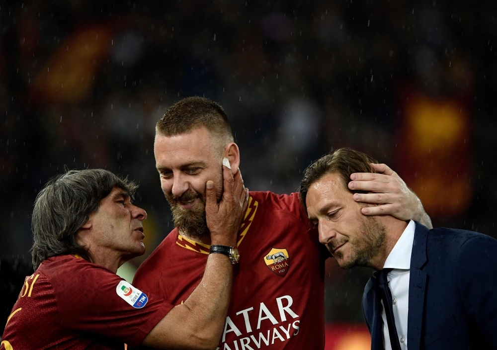 Roma's midfielder Daniele De Rossi, center, is congratulated by former captain Francesco Totti, right, and Roma's forward Bruno Conti, left, during his farewell to Roma after 18 years at his home-town club after the Italian Serie A football match between Roma and Parma at the Olympic Stadium in Rome on Sunday. — AFP