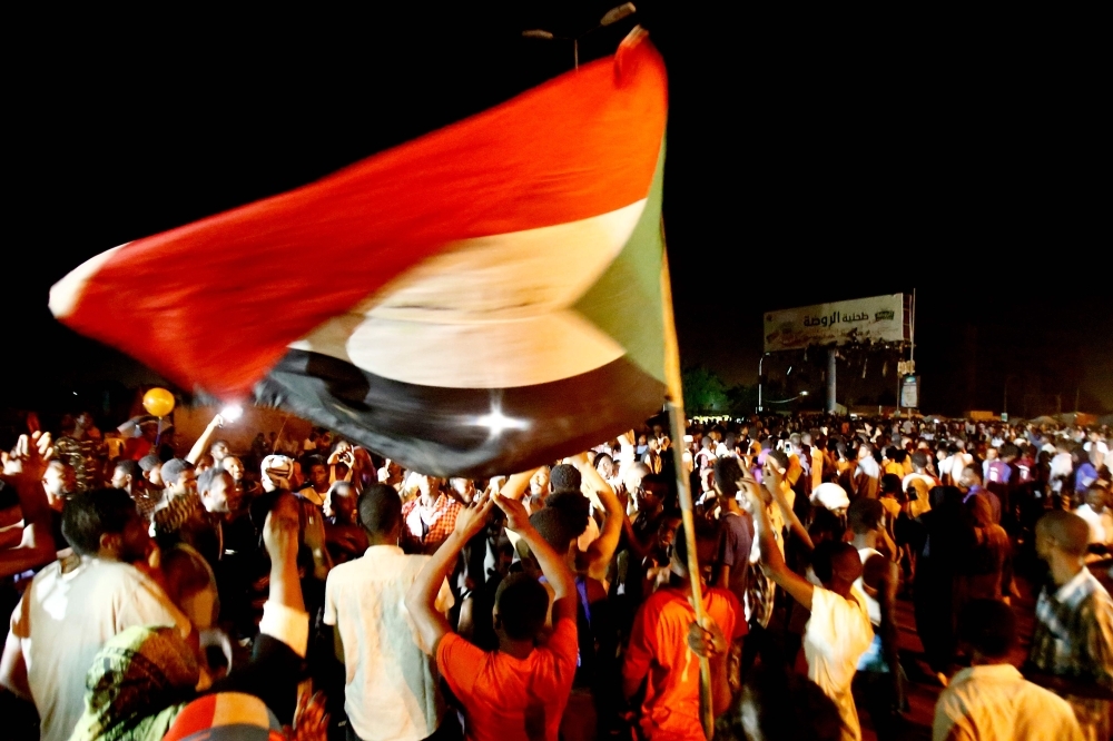 Sudanese wave flags and chant slogans as they gather during a demonstration outside the army headquarters in Khartoum on Thursday. — AFP