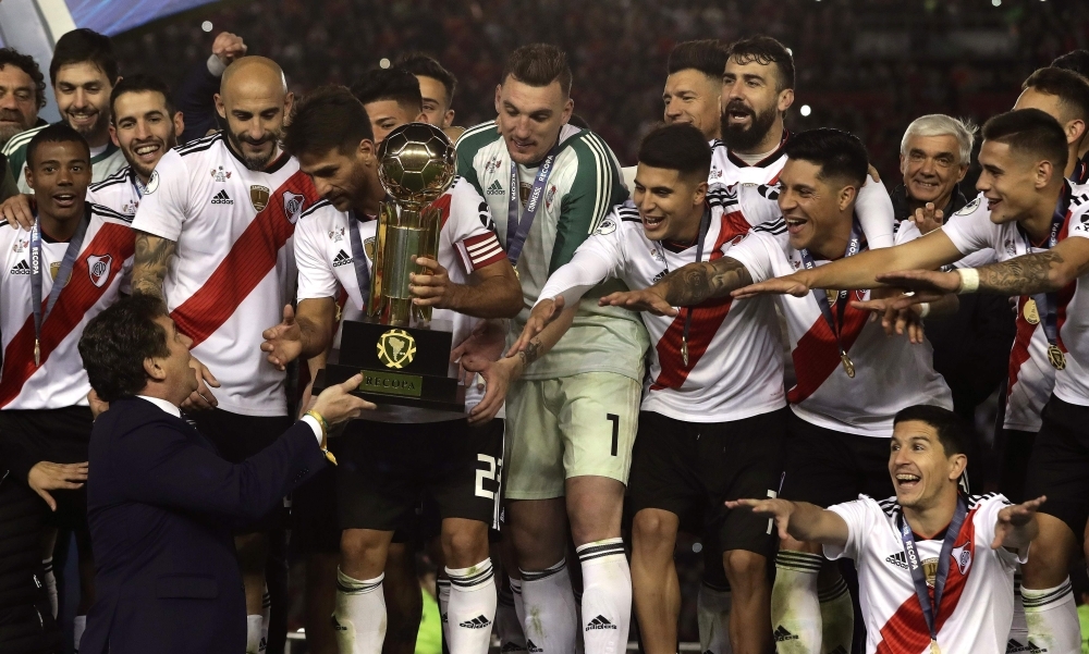 Argentina's River Plate footballers receive the trophy from CONMEBOL's President, Alejandro Dominguez (L-bottom) after winning the 2019 Recopa Sudamericana football final match against Brazil's Athletico Paranaense at the Monumental stadium, in Buenos Aires on Thursday. River won 3-0. — AFP