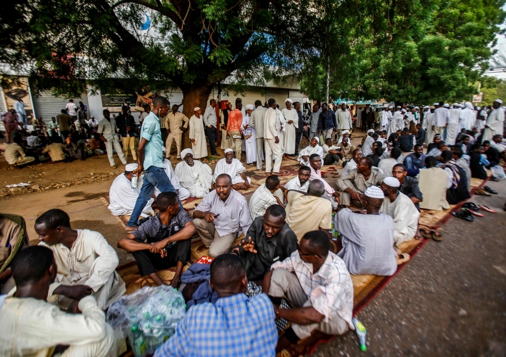 Sudanese supporters of the ruling Transitional Military Council (TMC) break their Ramadan fast together during a rally in the center of the capital Khartoum on Friday. — AFP