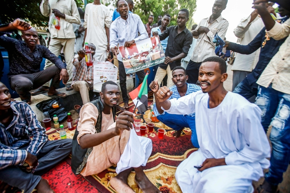 Sudanese supporters of the ruling Transitional Military Council (TMC) chant slogans as they break their Ramadan fast together during a rally in the center of the capital Khartoum on Friday. — AFP