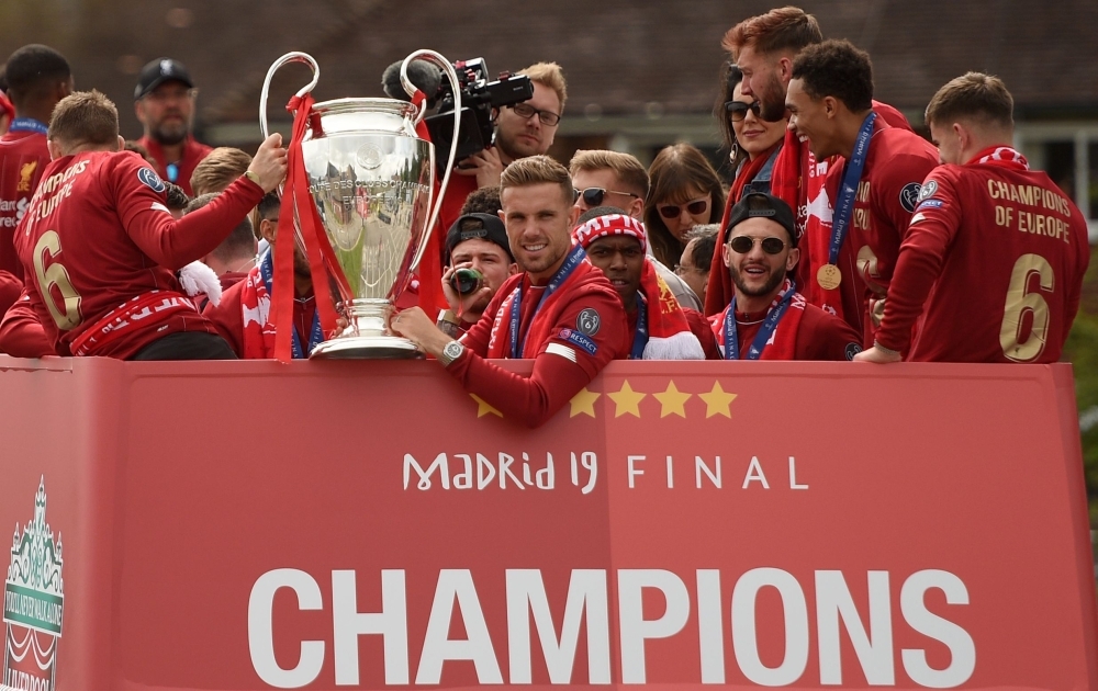 Liverpool's English midfielder Jordan Henderson (C) holds the European Champion Clubs' Cup trophy during an open-top bus parade around Liverpool, north-west England on Sunday, after winning the UEFA Champions League final football match between Liverpool and Tottenham. Liverpool's celebrations stretched long into the night after they became six-time European champions with goals from Mohamed Salah and Divock Origi to beat Tottenham — and the party was set to move to England on Sunday where tens of thousands of fans awaited the team's return. — AFP