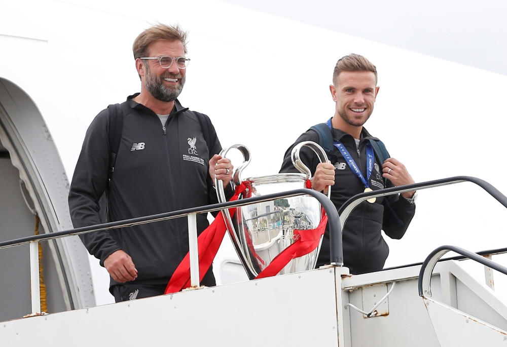 Liverpool's English midfielder Jordan Henderson (C) holds the European Champion Clubs' Cup trophy during an open-top bus parade around Liverpool, north-west England on Sunday, after winning the UEFA Champions League final football match between Liverpool and Tottenham. Liverpool's celebrations stretched long into the night after they became six-time European champions with goals from Mohamed Salah and Divock Origi to beat Tottenham — and the party was set to move to England on Sunday where tens of thousands of fans awaited the team's return. — AFP
