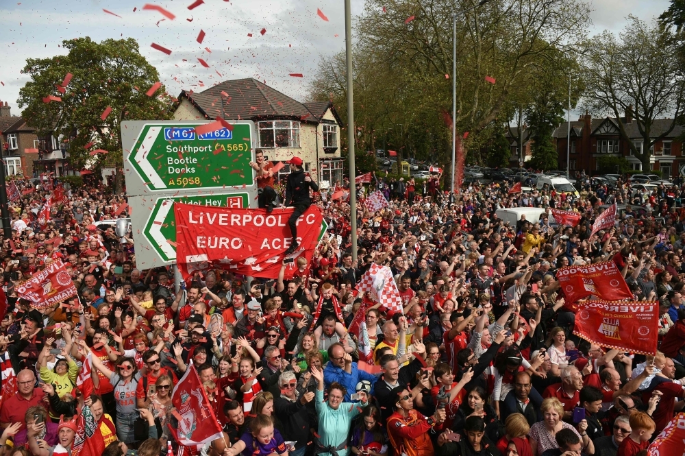 Liverpool's English midfielder Jordan Henderson (C) holds the European Champion Clubs' Cup trophy during an open-top bus parade around Liverpool, north-west England on Sunday, after winning the UEFA Champions League final football match between Liverpool and Tottenham. Liverpool's celebrations stretched long into the night after they became six-time European champions with goals from Mohamed Salah and Divock Origi to beat Tottenham — and the party was set to move to England on Sunday where tens of thousands of fans awaited the team's return. — AFP