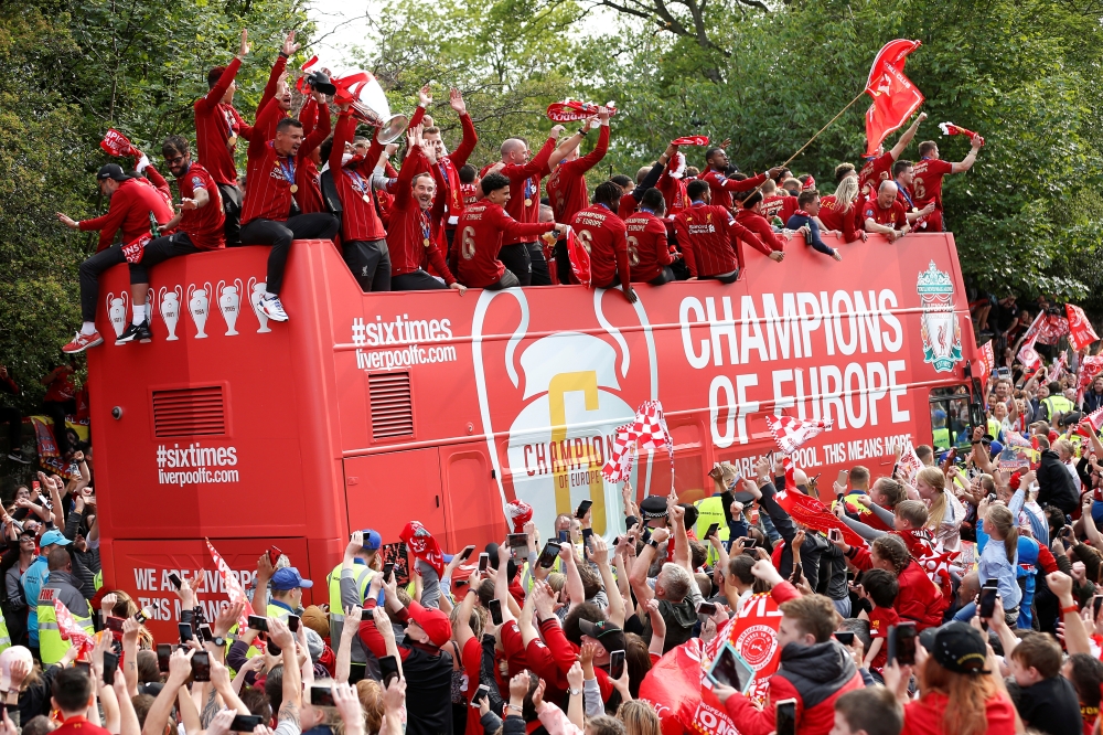 Liverpool's English midfielder Jordan Henderson (C) holds the European Champion Clubs' Cup trophy during an open-top bus parade around Liverpool, north-west England on Sunday, after winning the UEFA Champions League final football match between Liverpool and Tottenham. Liverpool's celebrations stretched long into the night after they became six-time European champions with goals from Mohamed Salah and Divock Origi to beat Tottenham — and the party was set to move to England on Sunday where tens of thousands of fans awaited the team's return. — AFP