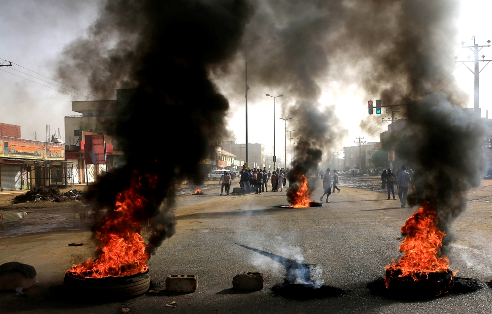 Sudanese protesters use burning tires to erect a barricade on a street in Khartoum on Monday. — Reuters 