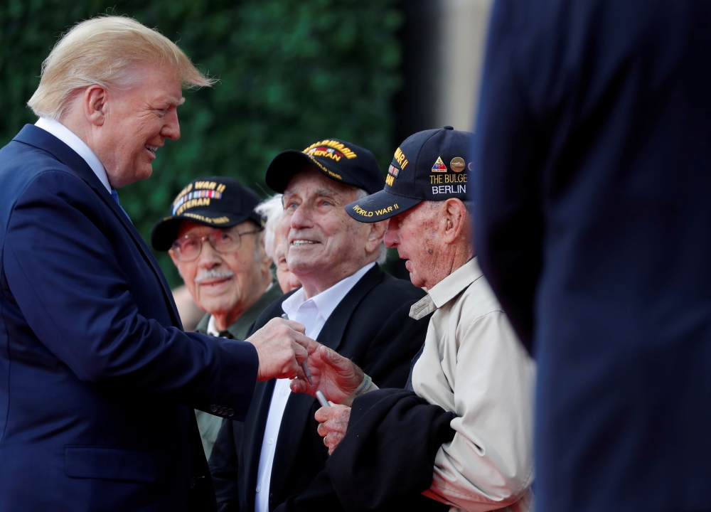 French President Emmanuel Macron helps a WWII veteran during the commemoration ceremony for the 75th anniversary of D-Day at the American cemetery of Colleville-sur-Mer in Normandy, France, Thursday. — Reuters
