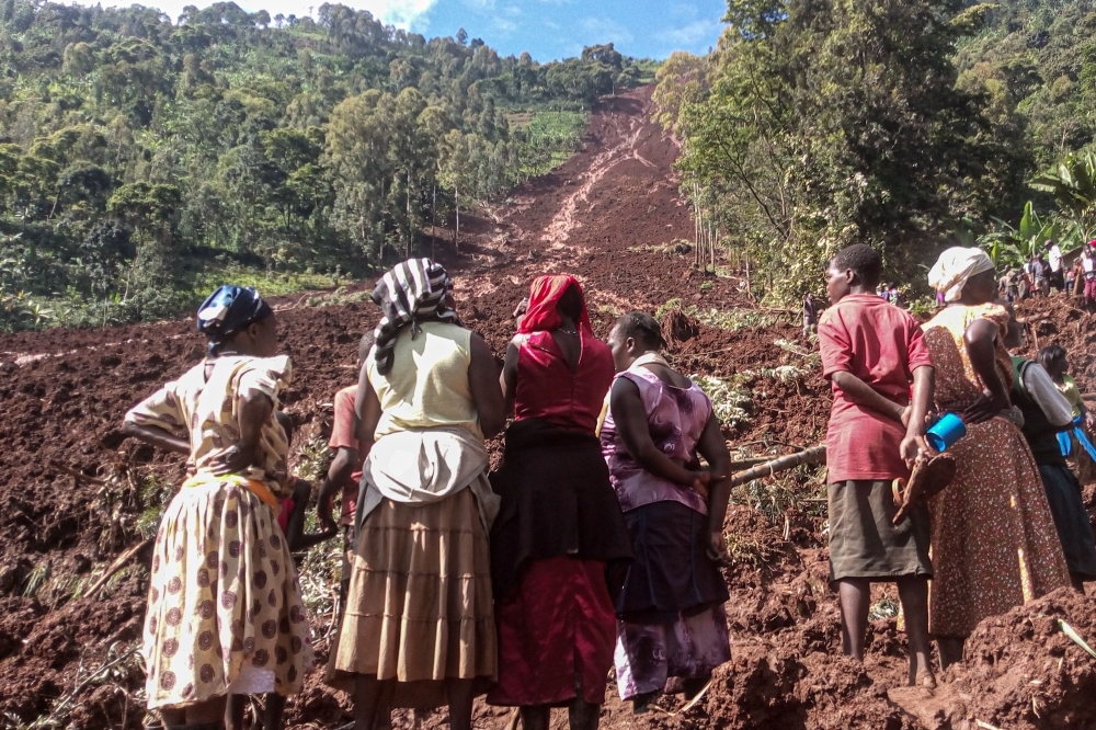 Women stand and look at a landslide site in Shisakali village of Bududa district, eastern Uganda, on Wednesday. — AFP