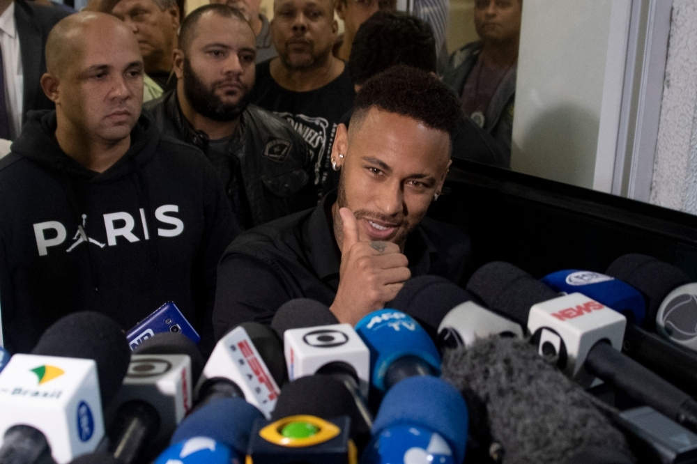 Brazil's star striker Neymar gives the thumb up as he leaves a Police Station after giving a statement to police for posting intimate WhatsApp messages with Najila Trindade Mendes de Souza, who has accused of rape, on social media, at the Internet Crime Special Police Unit in Rio de Janeiro, Brazil on Thursday. — AFP