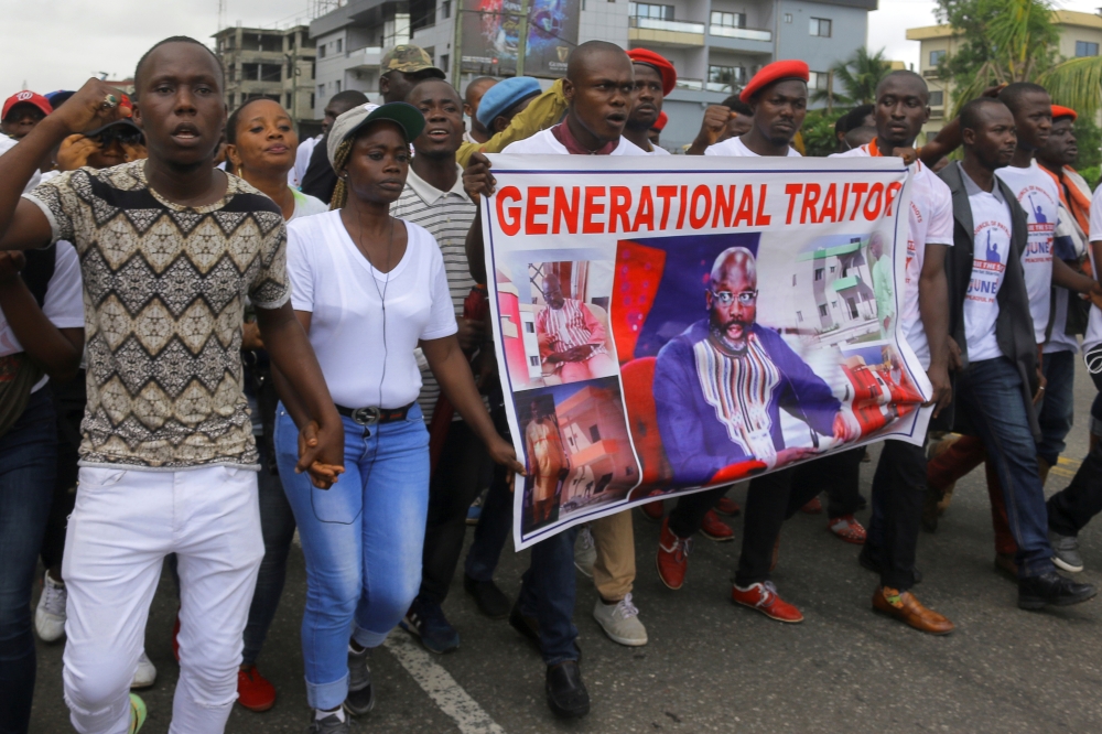 People carry a banner depicting Liberia's President George Weah as they march during a protest to voice discontent toward the presidency of Weah, whose policies they see as having failed to curb economic decline and mitigate corruption. — Reuters