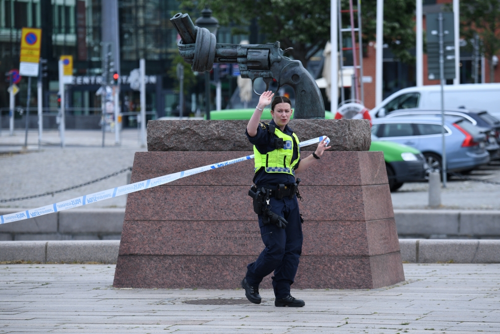 A police member gestures at Malmo central station after police shot a man for 