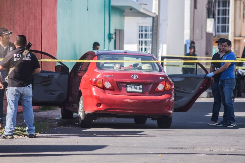 Ministerial police officers inspect the vehicle in which Mexican journalist Marcos Miranda Cogco was riding her granddaughter to school when he was kidnapped by armed men, in Boca del Rio, Veracruz State, Mexico, on Wednesday. — AFP