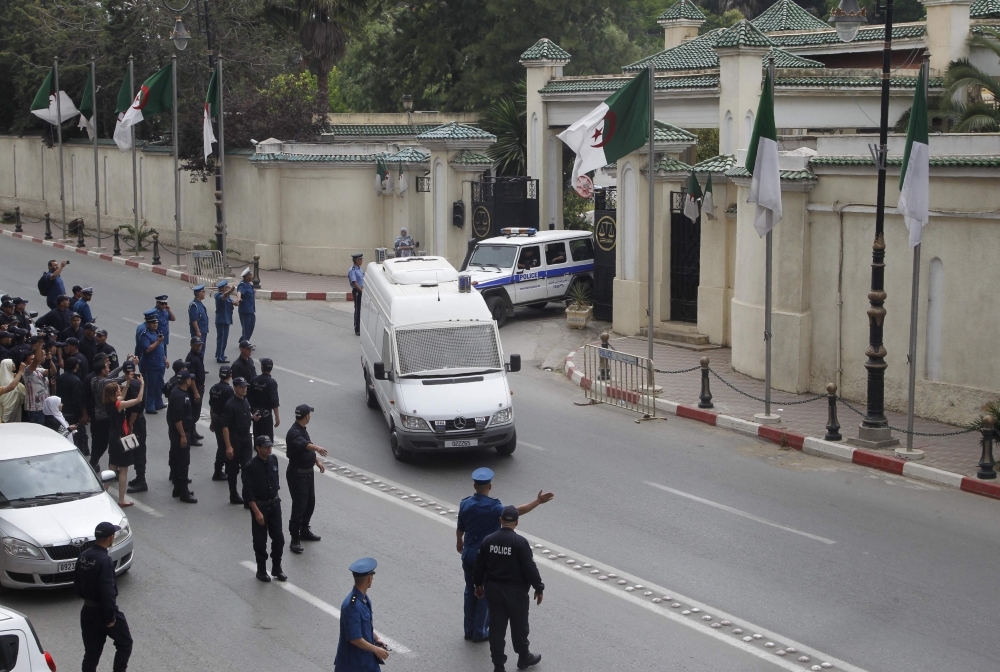 Members of the Algerian security forces escort the vehicle (white) transporting former Prime Minister Ahmed Ouyahia from the Supreme Court after a hearing in the capital Algiers on Wednesday. — AFP