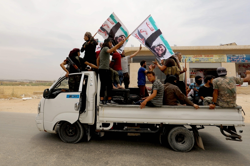 A convoy of Syrians follow the truck carrying the coffin of late rebel fighter Abdel-Basset Aal-Sarout on June 9, 2019, near the Bab Al-Hawa crossing point, northwestern Syria, on the way to his funeral after crossing the border from Turkey where he was receiving treatment following his injury earlier this week. — AFP