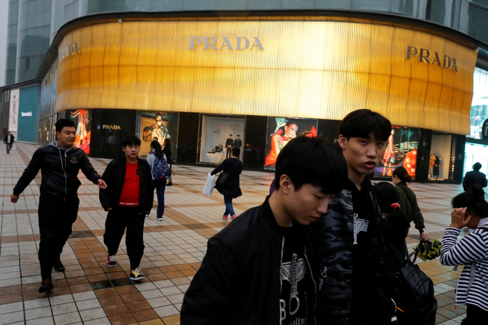 People walk past a Prada luxury fashion boutique near Wangfujing Street, a pedestrianized shopping area, in Beijing, China in this Oct. 15, 2018, file photo. — Reuters