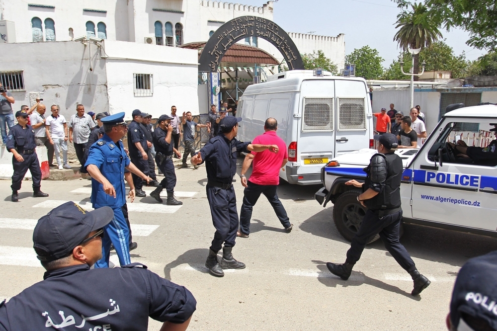 A Protester is pushed back by policemen as Algeria's former prime minister Abdelmalek Sellal is driven to custody at the El Harrach prison in the suburbs of the capital Algiers, on Thursday. Sellal was remanded in custody after appearing before a judge as part of an anti-corruption investigation, state media reported. — AFP