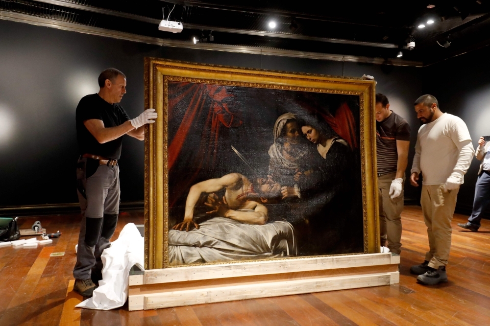 Workers carry a painting believed by some experts to be Caravaggio's 