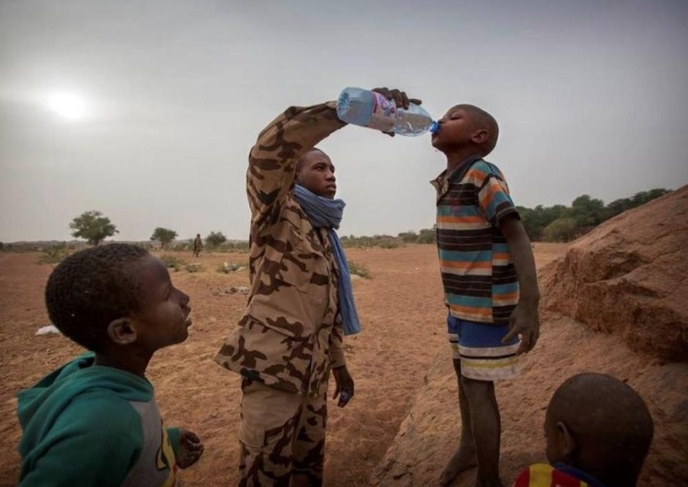 A member of MINUSMA Chadian contingent gives water to a boy in Kidal, Mali December 17, 2016. — Reuters