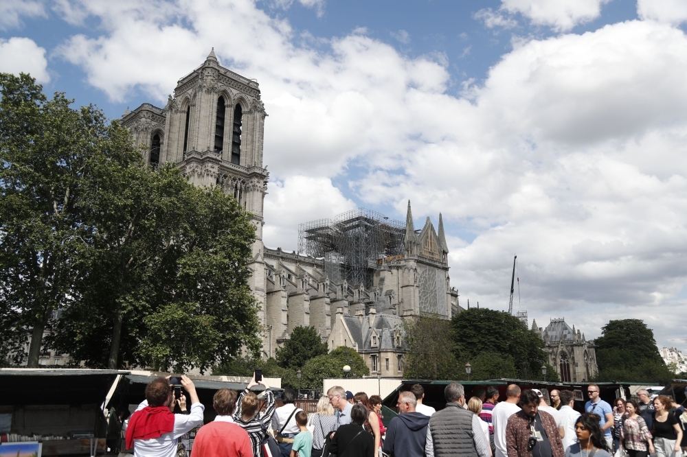 People walk along the banks of the River Seine past the Notre-Dame de Paris cathedral, in Paris on Saturday. — AFP