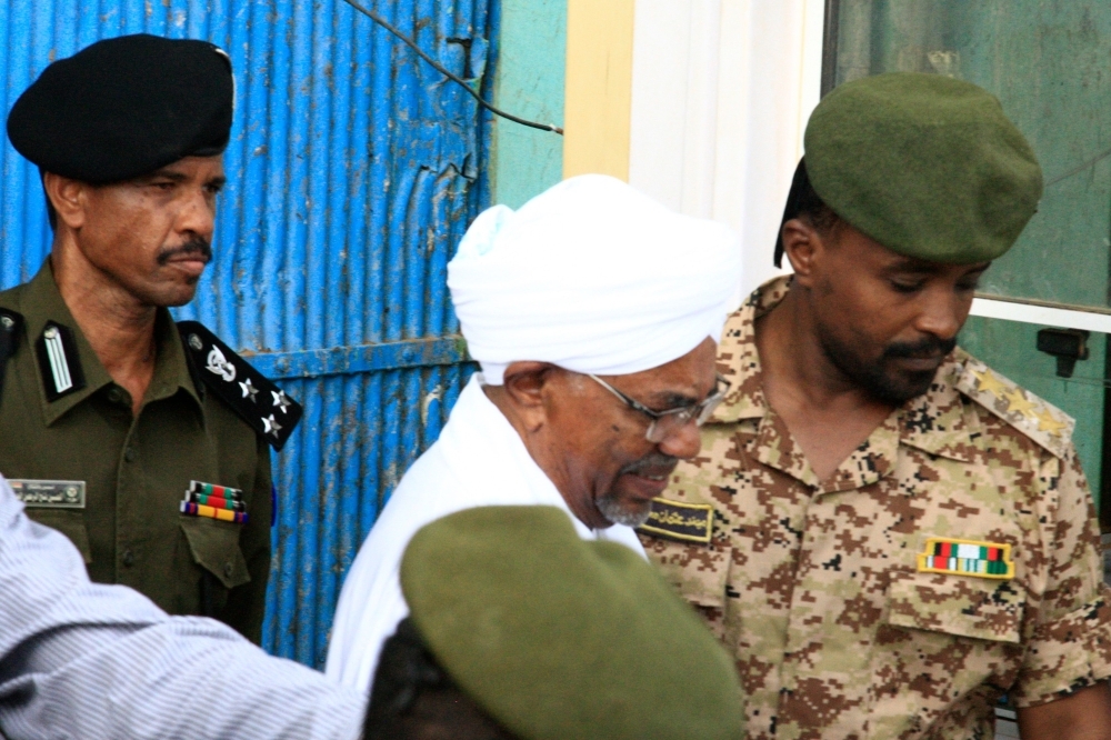Sudan's ousted president Omar Al-Bashir is escorted into a vehicle as he returns to prison following his appearance before prosecutors over charges of corruption and illegal possession of foreign currency, in the capital Khartoum on Sunday. — AFP