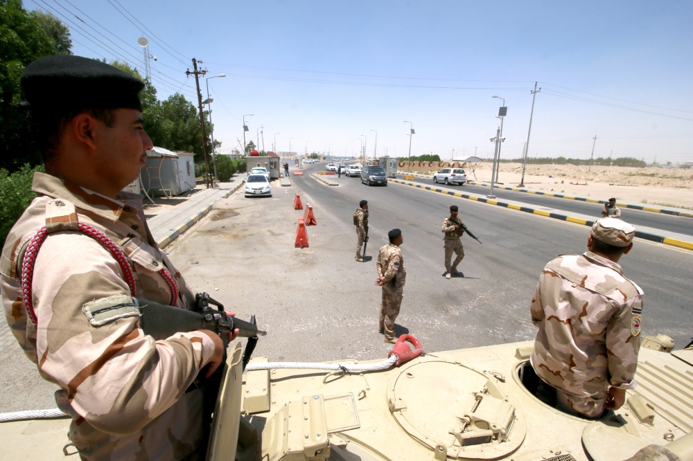 Iraqi soldiers stay guard at the entry of Zubair oilfield after a rocket struck the site of residential and operations headquarters of several oil companies, at Burjesia area in Basra on Wednesday. — Reuters