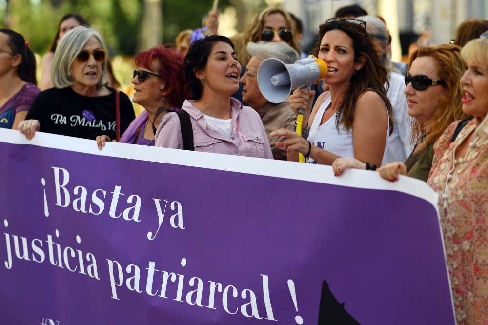 A group of women hold a banner reading 