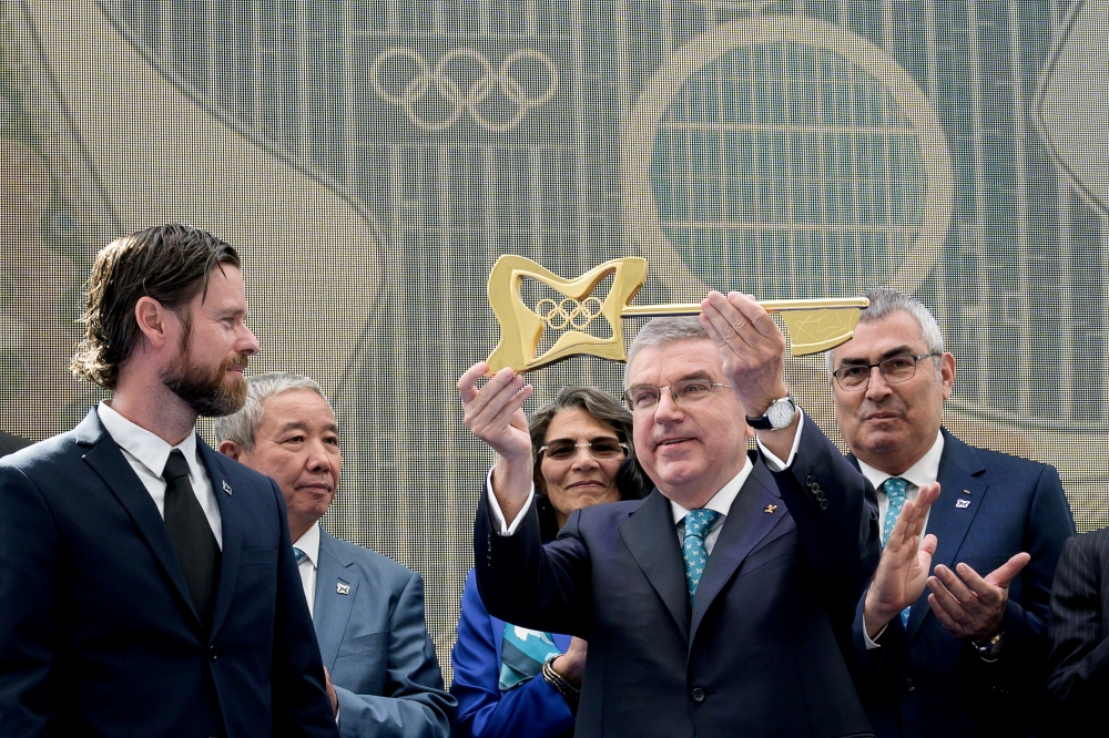 International Olympic Committee (IOC) President Thomas Bach (C) raises the key next to senior architect Jan Ammundsen (L) during the inauguration of the new IOC headquarters in Lausanne, Switzlerland, Sunday ahead of the decision on 2026 Winter Games host. — Reuters