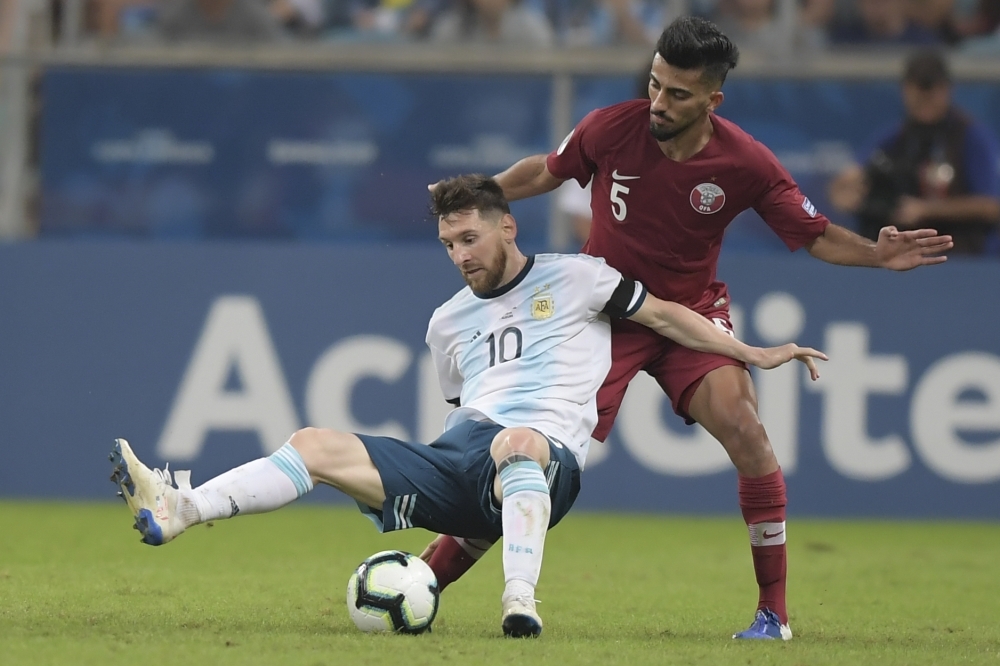 Argentina's Lionel Messi (L) and a Qatari defender  vie for the ball during their Copa America football tournament group match at the Gremio Arena in Porto Alegre, Brazil, on Sunday. — AFP