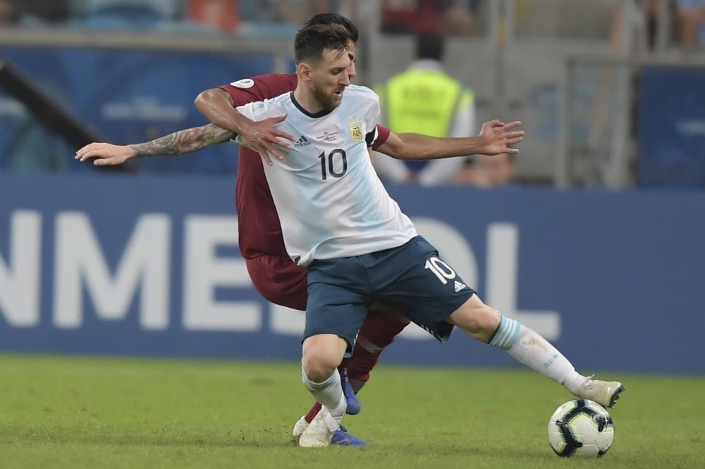 Argentina's Lionel Messi (L) and a Qatari defender  vie for the ball during their Copa America football tournament group match at the Gremio Arena in Porto Alegre, Brazil, on Sunday. — AFP