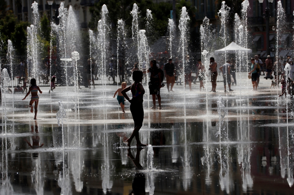 People cool off in water fountains in Nice as a heat wave is expected in much of the country, France, on Monday. — Reuters