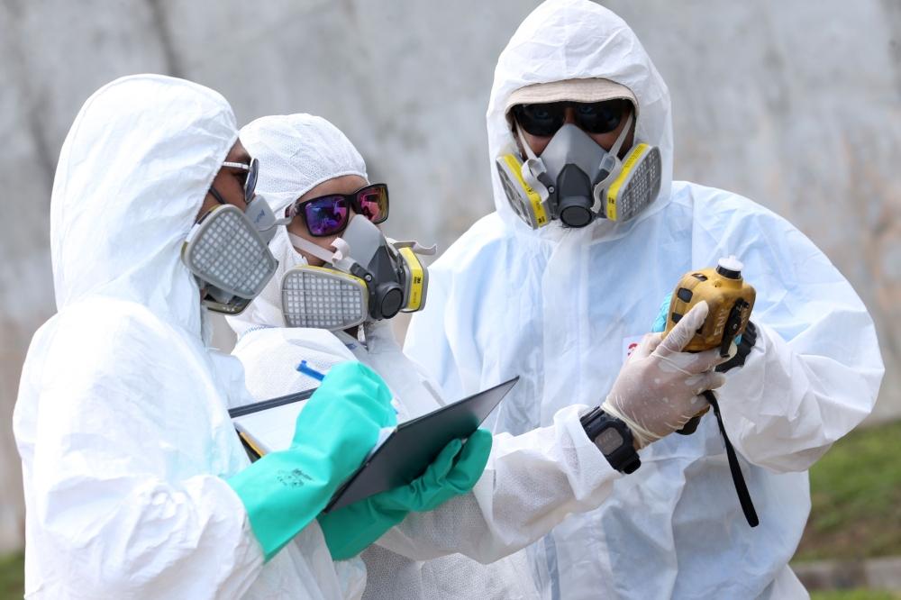 Emergency personnel wearing protective suits check the air quality in Pasir Gudang on Tuesday, after toxic fumes were reported in the area. - AFP