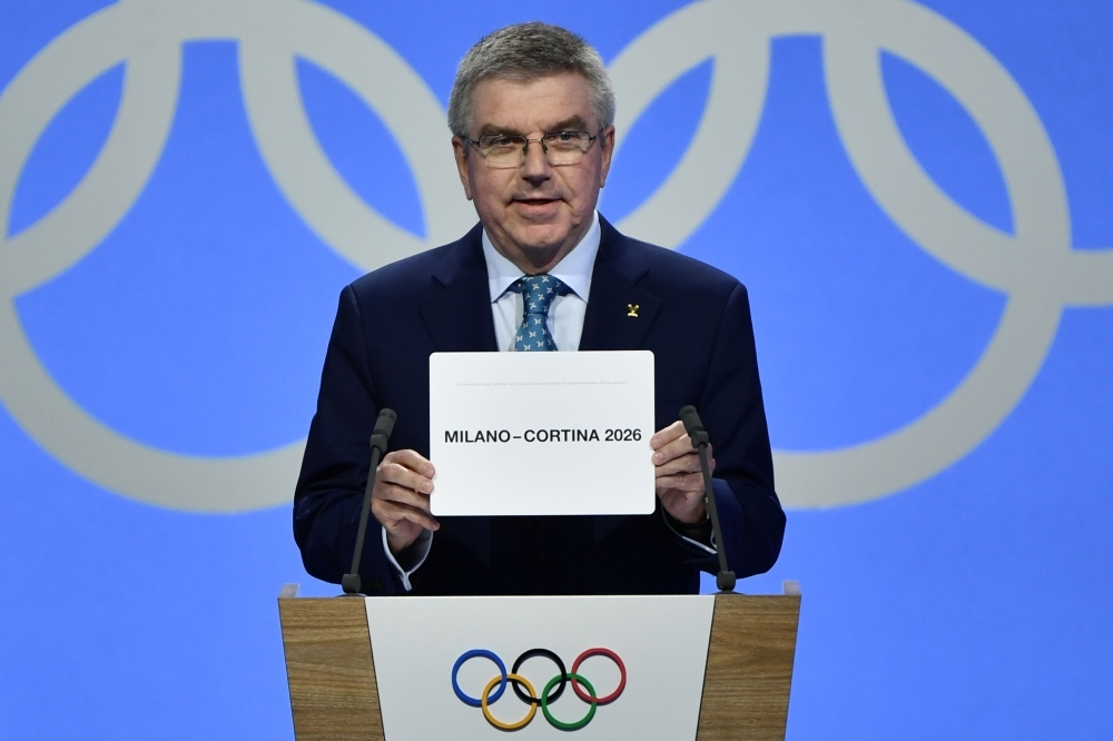 International Olympic Committee (IOC) president Thomas Bach shows the card with the name Milan/Cortina d'Ampezzo as the winning name of the 2026 Winter Olympics during the 134th session of the International Olympic Committee (IOC), in Lausanne on Monday. — AFP