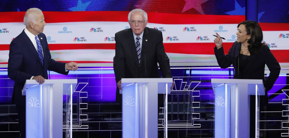 Former Vice President Joe Biden, left, and Senator Kamala Harris, right debate racial issues as Senator Bernie Sanders, center, listens during the second night of the first US Democratic presidential candidates 2020 election debate in Miami, Florida, on Thursday. — Reuters