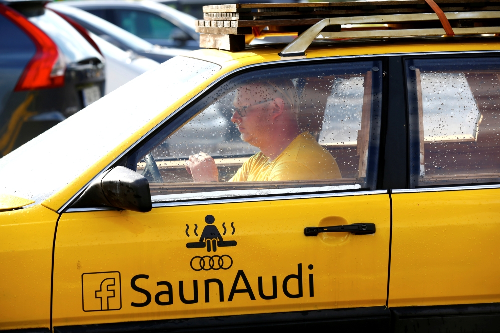 Willem Maesalu, inventor and owner of the old yellow Audi car converted into a small sauna, drives in the parking lot in Tallinn, Estonia, on Thursday. — Reuters
