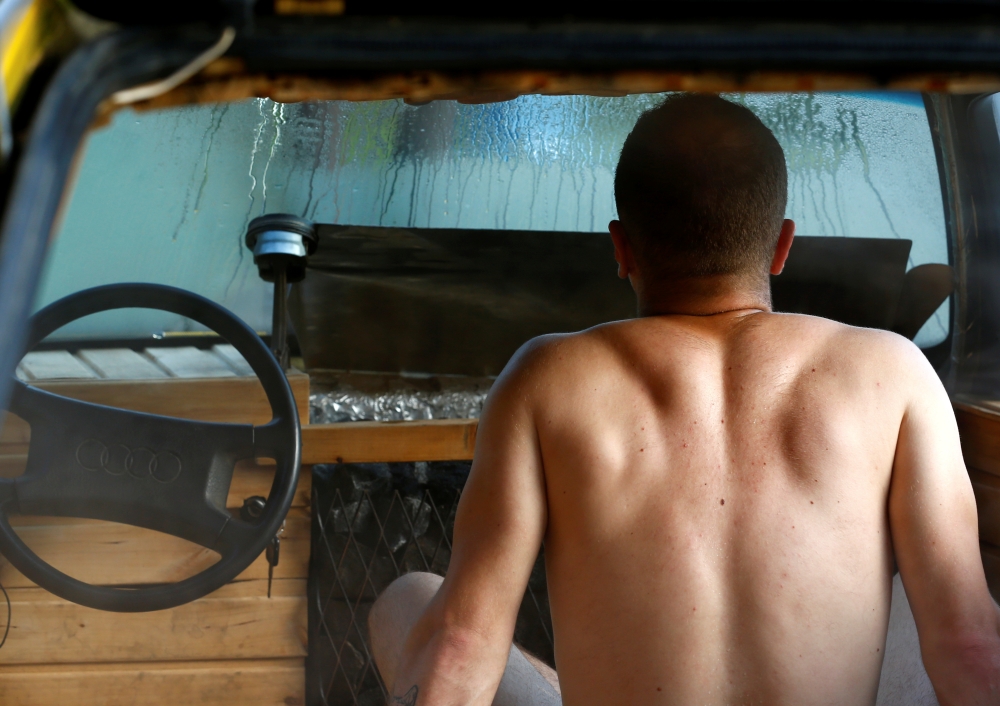Willem Maesalu, inventor and owner of the old yellow Audi car converted into a small sauna, drives in the parking lot in Tallinn, Estonia, on Thursday. — Reuters