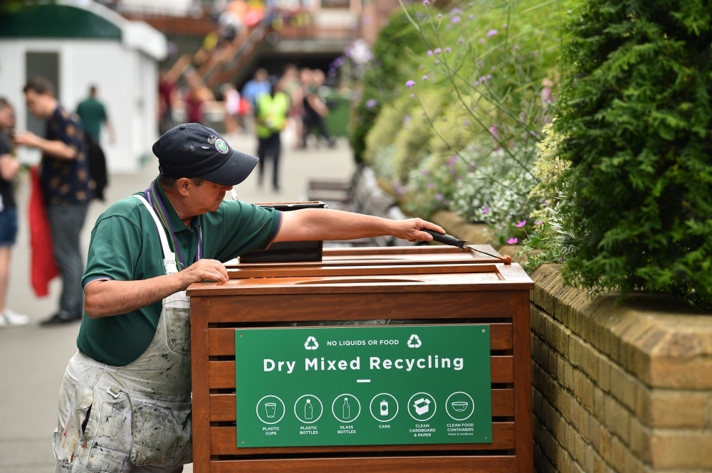 A worker puts touches up the finish on a recycling bin at The All England Tennis Club in Wimbledon, southwest London, on Sunday, on the eve of the start of the 2019 Wimbledon Championships tennis tournament. — AFP