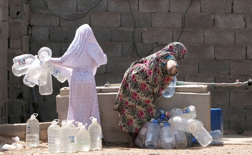 A Libyan woman displaced from the town of Tawergha fills containers with water at a displaced camp in Benghazi, Libya, in this June 19, 2019 file photo. — Reuters