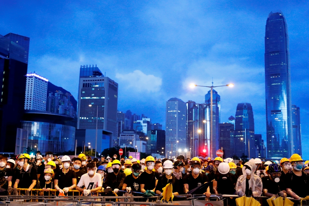 Anti-extradition bill protesters stand behind a barricade during a demonstration near a flag raising ceremony for the anniversary of Hong Kong handover to China in Hong Kong, on July 1. -Reuters