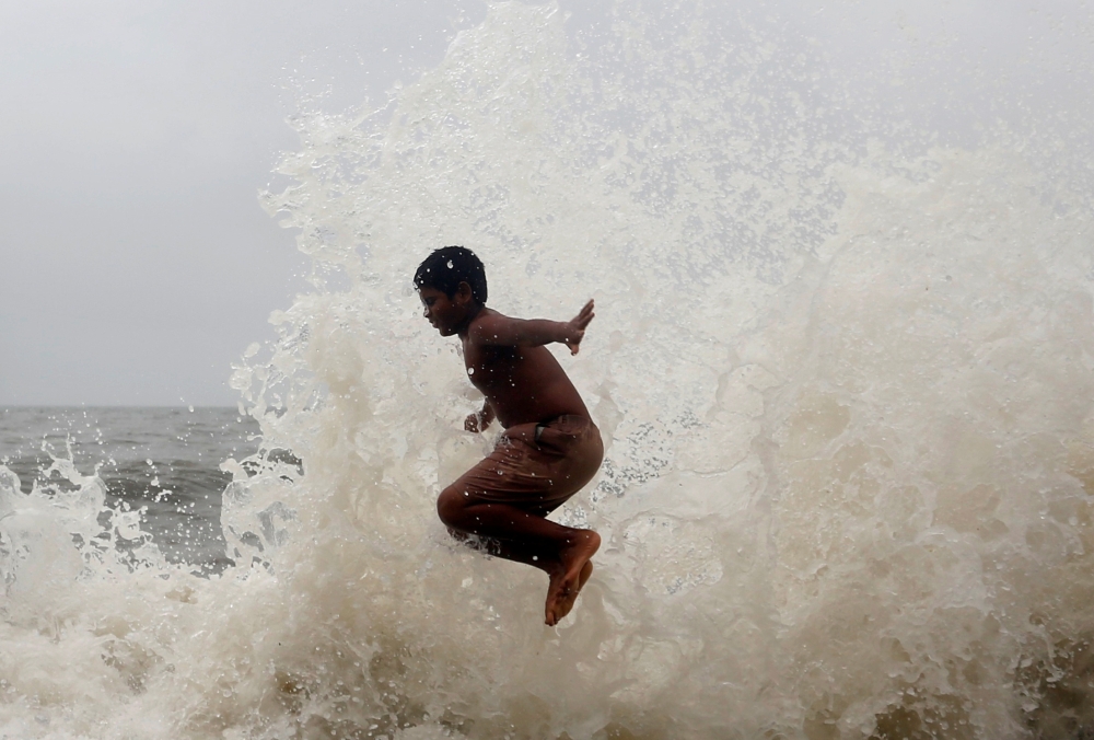 A boy plays as huge waves hit a seafront during high tide in Mumbai, India, on Thursday. — Reuters