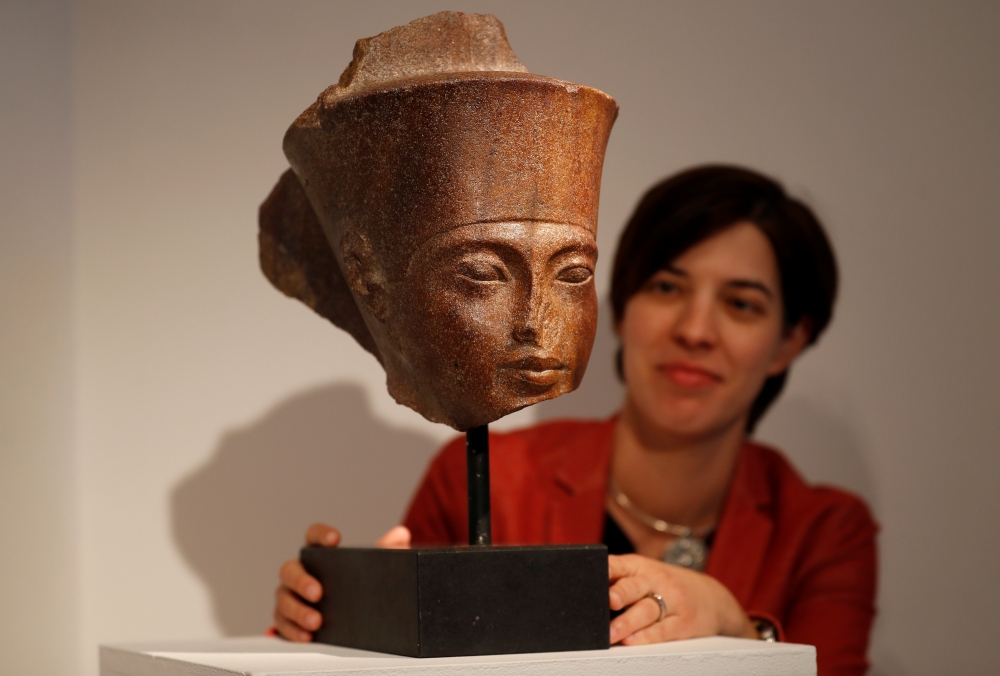 Laetitia Delaloye, head of antiquities of Christie's, poses for a photograph with an Egyptian brown quartzite head of the God Amen prior to its' sale at Christie's auction house in London, Britain, on Thursday. — Reuters