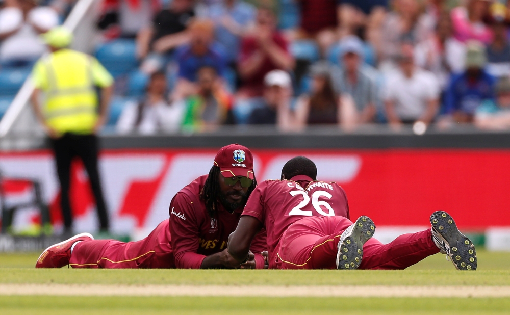 West Indies' Chris Gayle celebrates with Carlos Brathwaite after catching out Afghanistan's Rahmat Shah during the ICC Cricket World Cup match at Headingley, Leeds, Britain on Thursday. — Reuters
