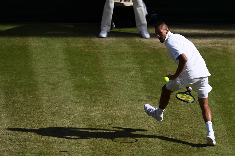Australia's Nick Kyrgios plays a shot between his legs against Spain's Rafael Nadal during their men's singles second round match on the fourth day of the 2019 Wimbledon Championships at The All England Lawn Tennis Club in Wimbledon, southwest London, on Thursday. — AFP