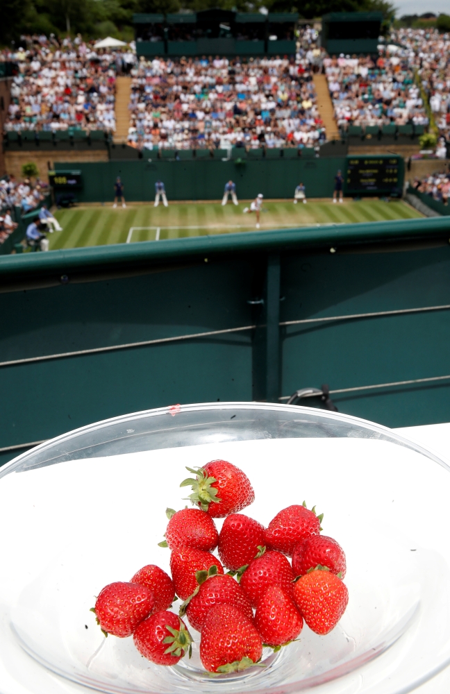 General view of a bowl of strawberries as a match is played in the background. — Reuters