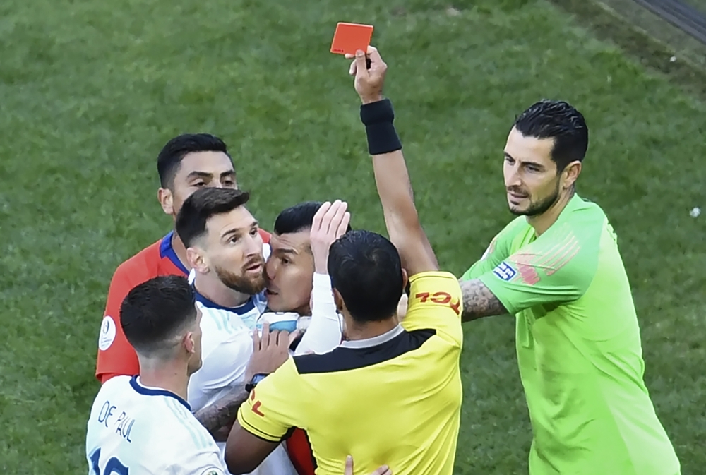 Paraguayan referee Mario Diaz de Vivar shows the red card to Argentina's Lionel Messi and Chile's Gary Medel as they have a physical encounter during the Copa America football tournament third-place match at the Corinthians Arena in Sao Paulo, Brazil, on Saturday. — AFP