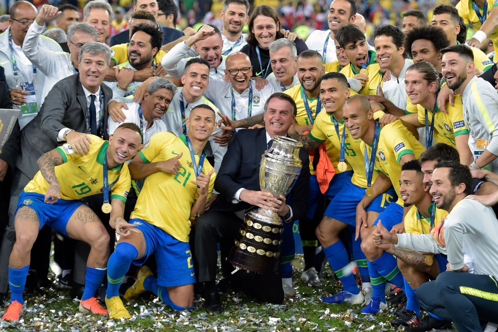  Brazilian President Jair Bolsonaro holds the Copa America trophy as members of the Brazilian national team celebrates after winning the title by defeating Peru in the final match of the football tournament at Maracana Stadium in Rio de Janeiro, Brazil, on Sunday. — AFP